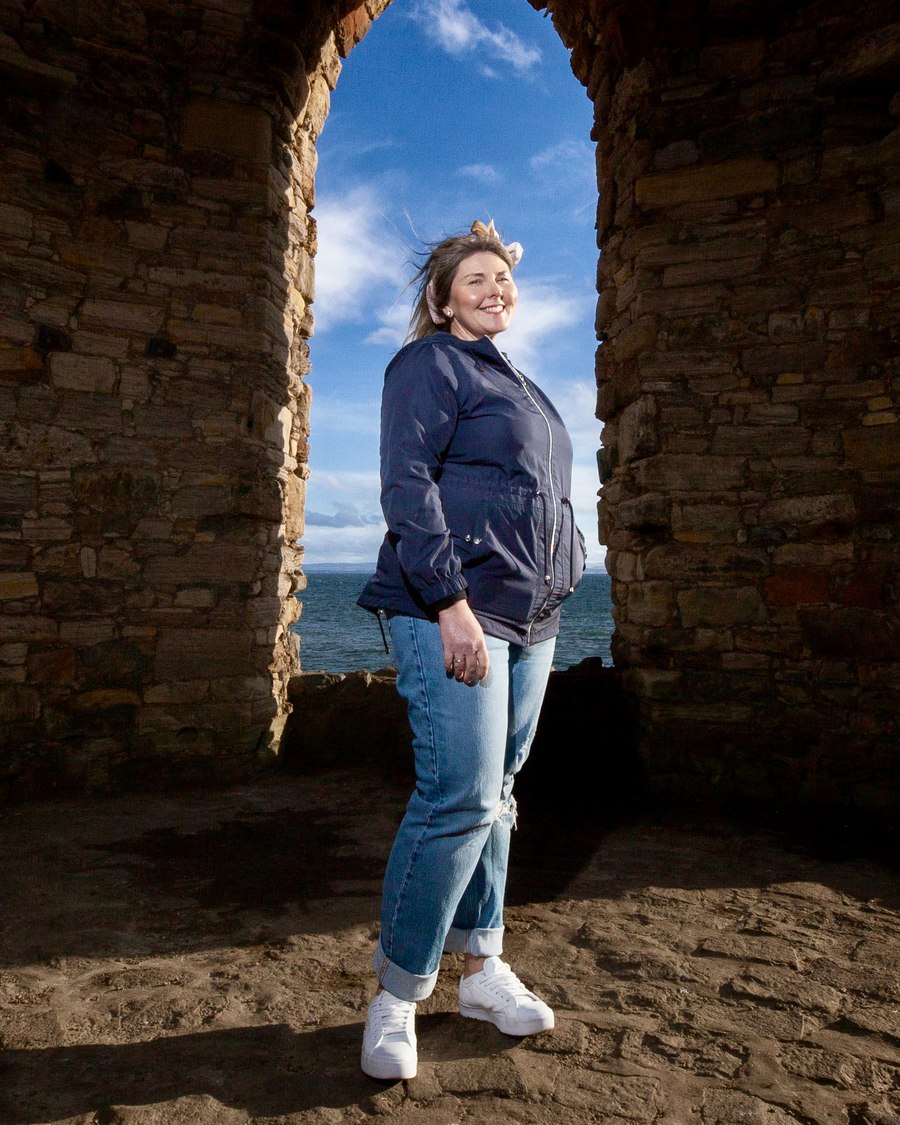 Karen, who looks after clients at Nine16, standing in a stone archway above the sea
