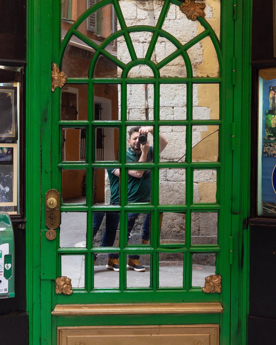 Thomas, the photographer behind Nine16, holding a camera reflected in an ornate mirrored door