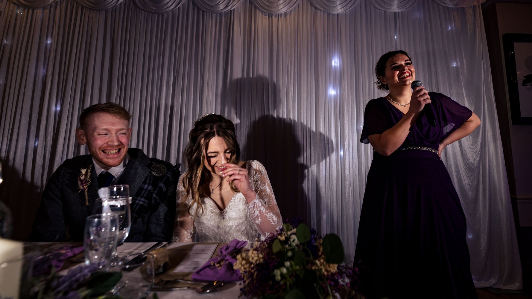 Newlyweds laughing during a reception speech