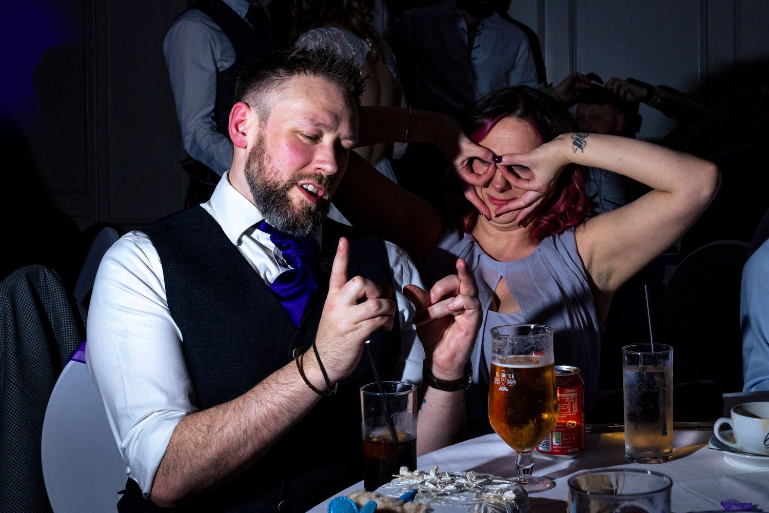 Couple sharing a laugh at the reception table with friends
