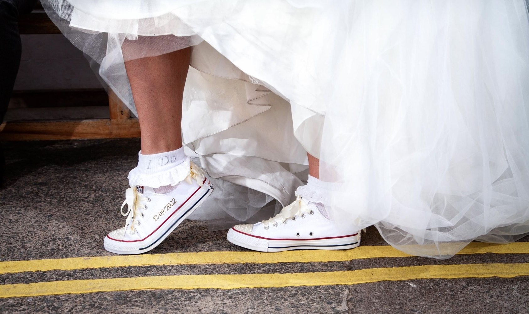 Bride's personalised sneakers peeking out from under her dress