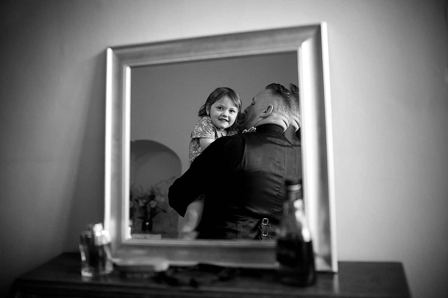 A father and daughter reflected in a mirror, sharing a smile