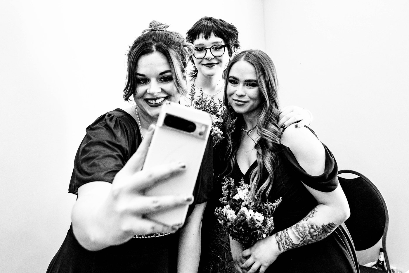 Three of the bridal party crowding into a selfie, in black and white