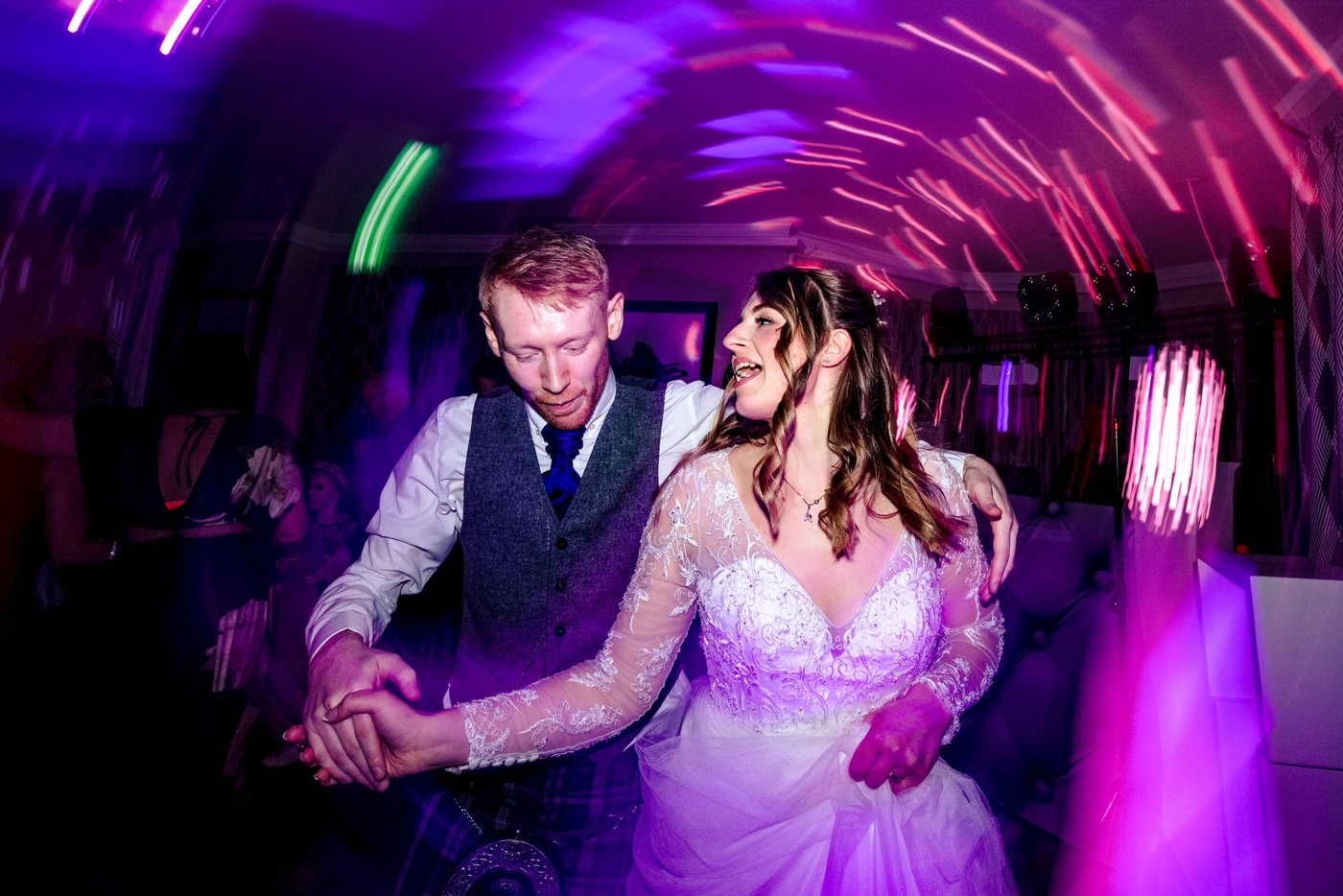 The couple dancing together under coloured light