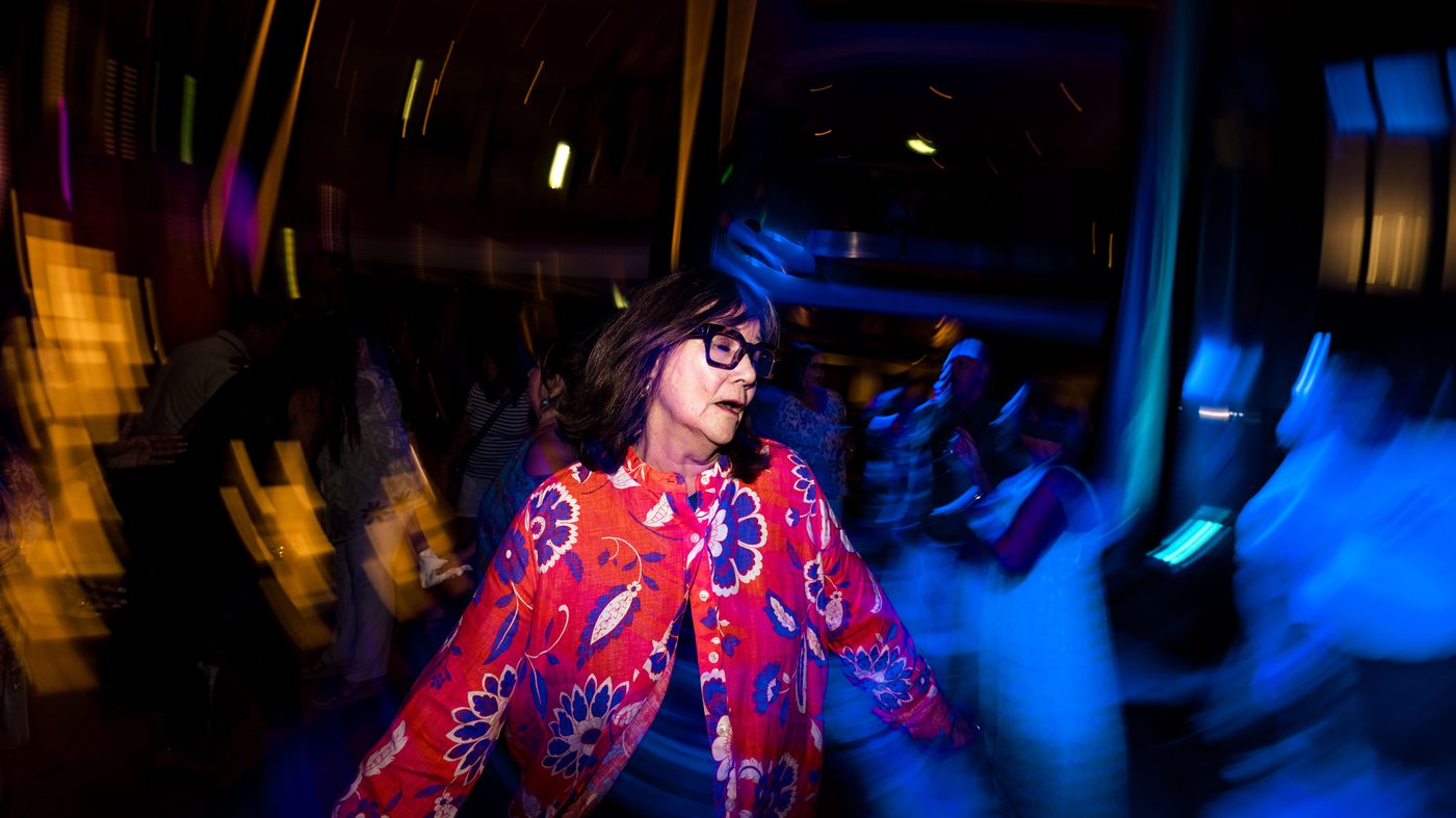 A guest dancing hard in a red patterned dress, light trails around her